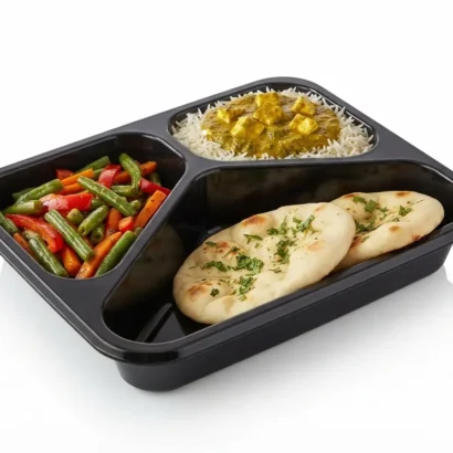 Black plastic 3-compartment tray with vegetables, rice and naan